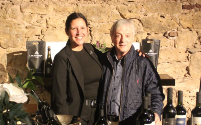 El Representante del Gobierno de Entre Rìos posa on una mujer delante de botellas de vino.