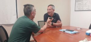 entrevistador de costado y entrevistado de frente alrededor de una mesa de reuniones.