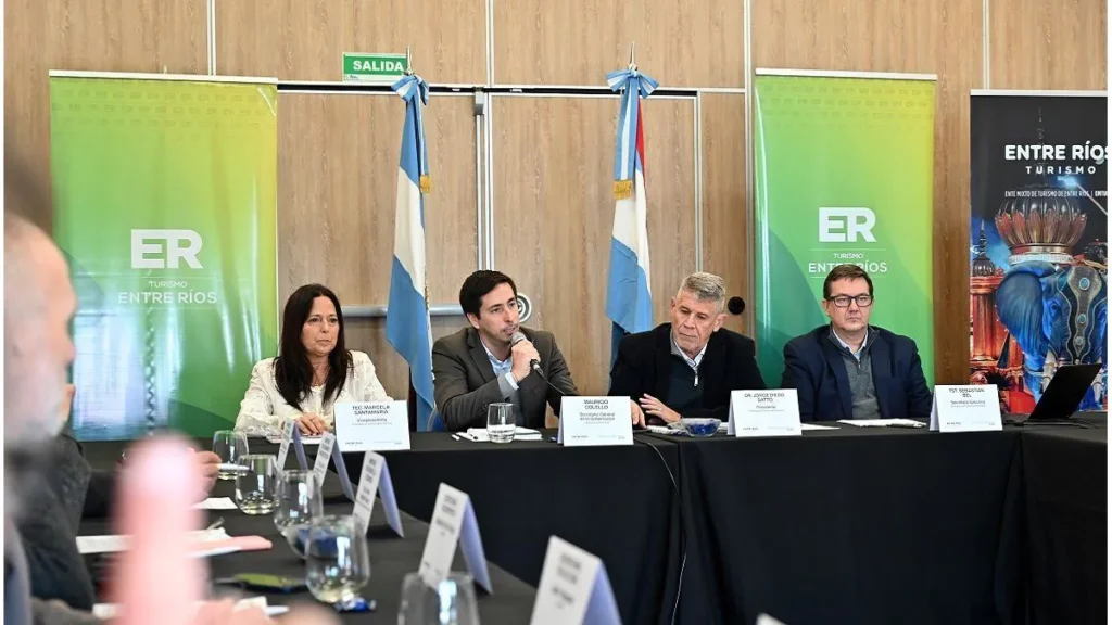 Con fondo de banderas argentina y entrerriana y banners del Gonierno de Entre Ríos exponen las autoridades del Ente mixto de turismo entrerriano